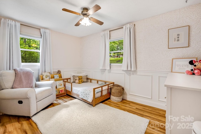 2044 Glenheath Dr, Hendersonville, NC 28791 - bedroom featuring multiple windows, wood finished floors, wainscoting, and a ceiling fan