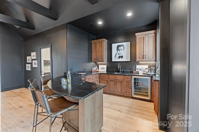 17416 Gillican Overlook Rd, Davidson, NC 28036 - kitchen with wine cooler, a peninsula, light wood-style flooring, a breakfast bar, and a sink