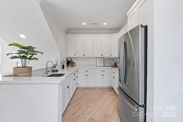 17416 Gillican Overlook Rd, Davidson, NC 28036 - kitchen with stainless steel fridge, a sink, a peninsula, light wood finished floors, and white cabinetry