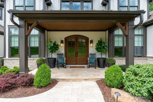 17416 Gillican Overlook Rd, Davidson, NC 28036 - view of exterior entry with french doors, a porch, board and batten siding, and stone siding