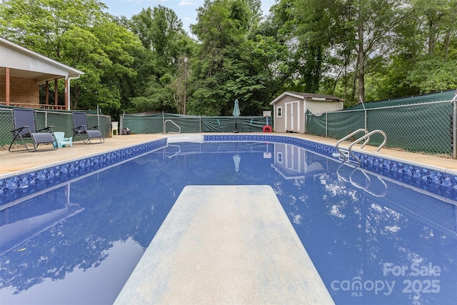 128 Paul Snipes Rd, Lancaster, SC 29720 - view of swimming pool featuring a fenced backyard, a diving board, a storage shed, view of wooded area, and an outdoor structure