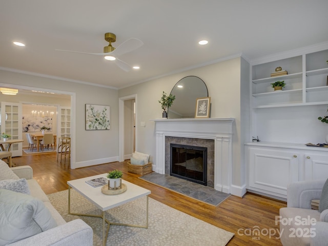 1069 Sedgefield Rd, Charlotte, NC 28209 - living area featuring a ceiling fan, a tiled fireplace, crown molding, wood finished floors, and recessed lighting