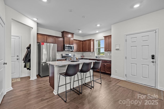 5207 Maynard Hill Dr, Monroe, NC 28110 - kitchen featuring appliances with stainless steel finishes, a sink, dark wood-style floors, a breakfast bar, and a center island