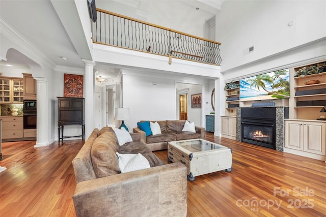 3932 Rounding Run Rd, Charlotte, NC 28277 - living room featuring a towering ceiling, decorative columns, light wood finished floors, a fireplace, and ornamental molding
