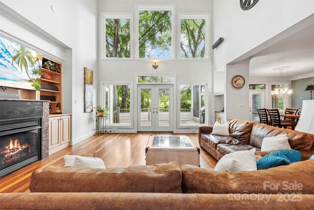 3932 Rounding Run Rd, Charlotte, NC 28277 - living room featuring wood finished floors, a chandelier, a towering ceiling, a glass covered fireplace, and healthy amount of natural light