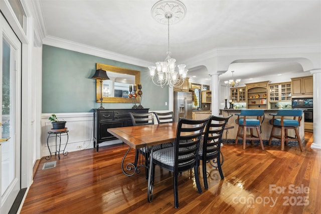 3932 Rounding Run Rd, Charlotte, NC 28277 - dining area featuring ornate columns, a chandelier, dark wood-type flooring, crown molding, and a wainscoted wall