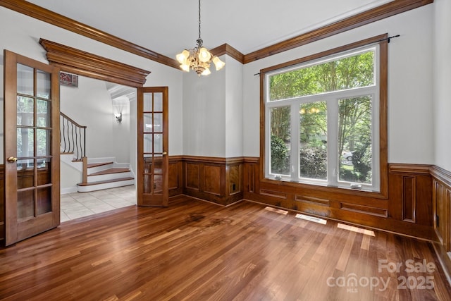 3932 Rounding Run Rd, Charlotte, NC 28277 - unfurnished dining area featuring french doors, a chandelier, wainscoting, crown molding, and wood finished floors