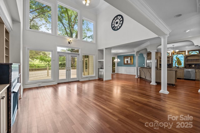 3932 Rounding Run Rd, Charlotte, NC 28277 - unfurnished living room featuring ornate columns, ornamental molding, a chandelier, dark wood-style flooring, and a high ceiling