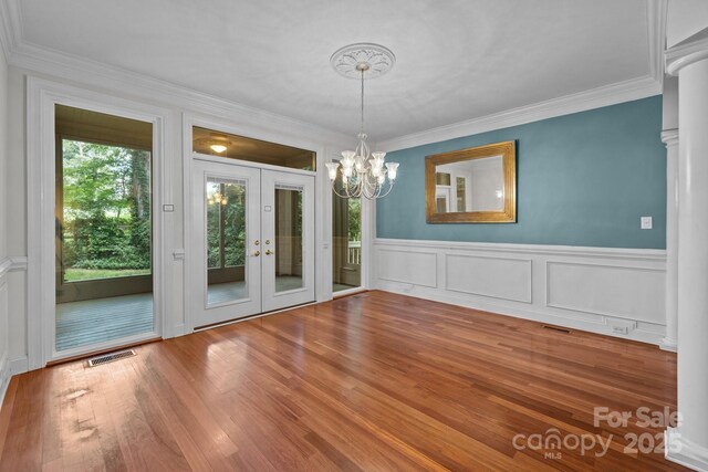 3932 Rounding Run Rd, Charlotte, NC 28277 - unfurnished dining area featuring french doors, ornate columns, a chandelier, ornamental molding, and wood finished floors