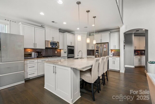8514 Ellington Park Dr, Charlotte, NC 28277 - kitchen featuring stainless steel appliances, arched walkways, decorative backsplash, white cabinetry, and crown molding