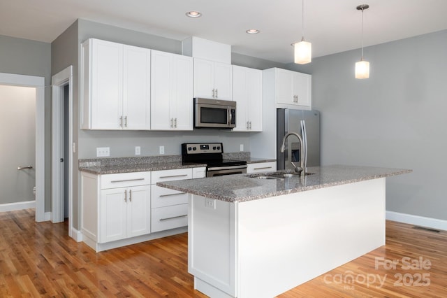 200 N Skyloft Dr Unit 2, Asheville, NC 28801 - kitchen with stainless steel appliances, a center island with sink, baseboards, white cabinetry, and light wood-style floors