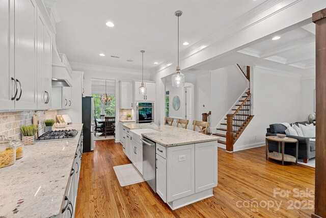 kitchen with stainless steel appliances, ornamental molding, light wood-type flooring, decorative backsplash, and white cabinets