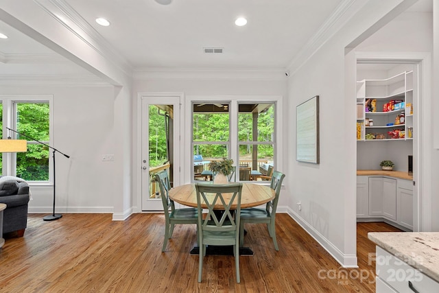 dining room featuring light wood-style floors, baseboards, ornamental molding, and recessed lighting
