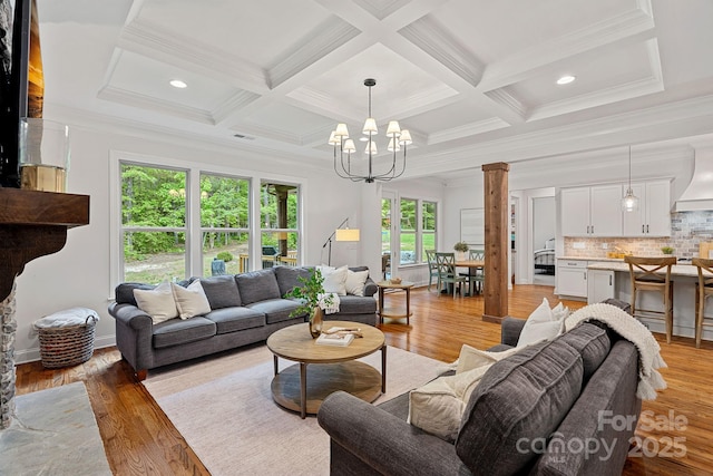 living room with a chandelier, ornamental molding, light wood-type flooring, coffered ceiling, and ornate columns