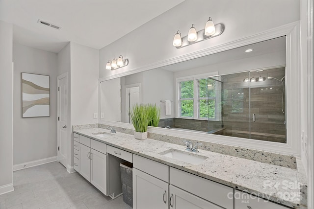 full bathroom featuring baseboards, a stall shower, double vanity, and tile patterned floors