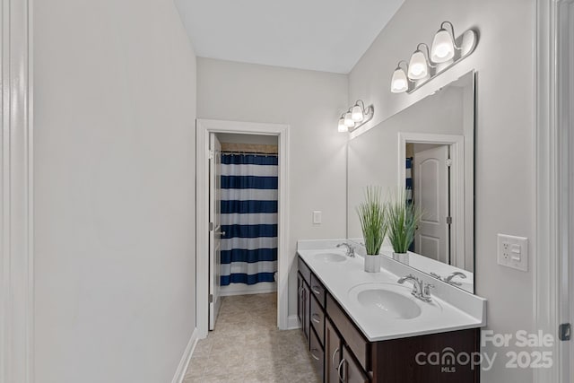 bathroom with baseboards and double vanity