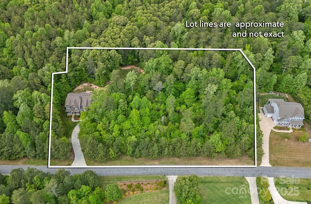 aerial view of property and surrounding area with a heavily wooded area and property parcel outlined
