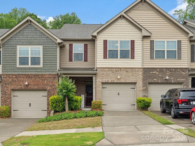 view of front of home with driveway, an attached garage, brick siding, and roof with shingles