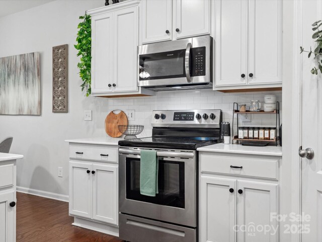 kitchen featuring appliances with stainless steel finishes, decorative backsplash, baseboards, light countertops, and white cabinets