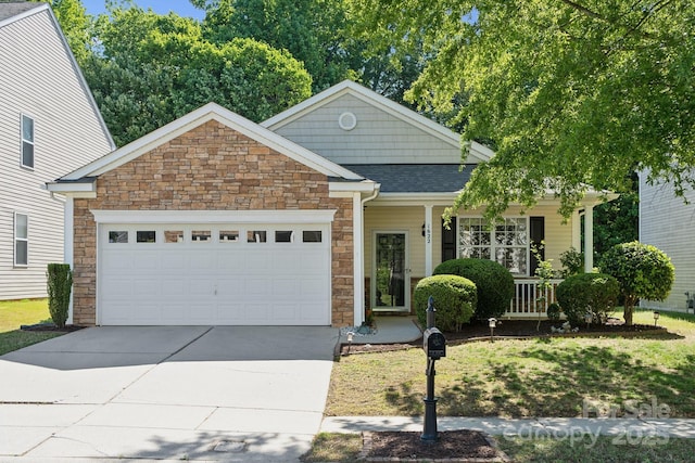 view of front facade with stone siding, an attached garage, a porch, driveway, and a shingled roof