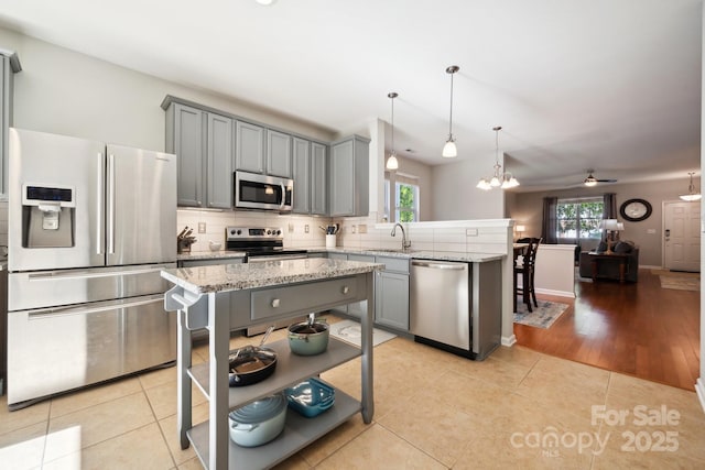 kitchen featuring appliances with stainless steel finishes, gray cabinetry, a peninsula, and decorative backsplash