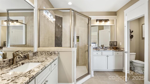 7324 Jolly Brook Dr, Charlotte, NC 28215 - full bath featuring a shower stall, tile patterned flooring, toilet, two vanities, and recessed lighting