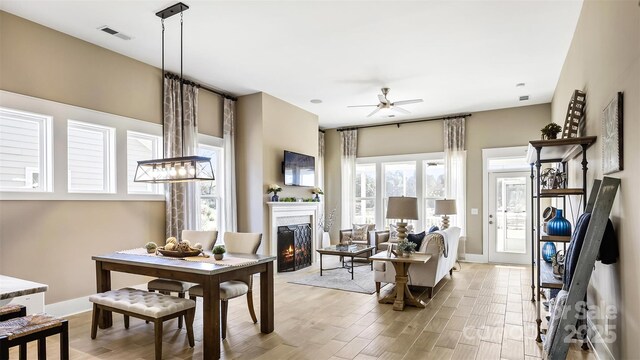 7324 Jolly Brook Dr, Charlotte, NC 28215 - dining space with a warm lit fireplace, light wood-style floors, ceiling fan, and baseboards