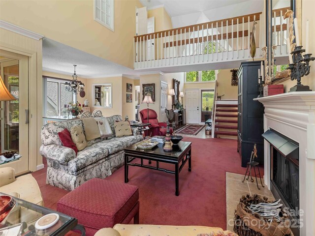carpeted living room with a fireplace, a towering ceiling, and crown molding