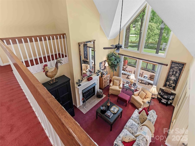 living area with high vaulted ceiling, carpet floors, a tile fireplace, and a ceiling fan
