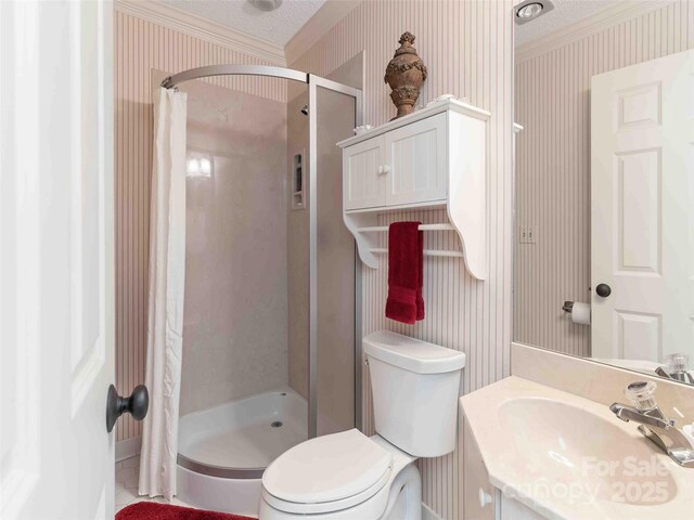 bathroom with wallpapered walls, a shower stall, crown molding, vanity, and toilet
