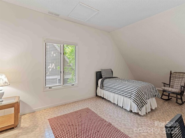 bedroom featuring attic access, vaulted ceiling, and baseboards