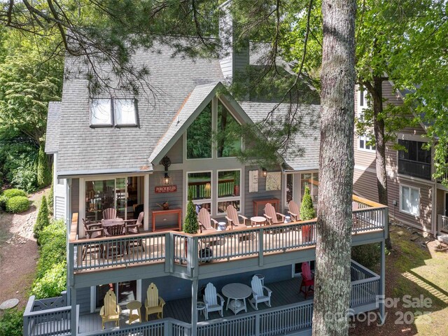 rear view of property featuring a deck and roof with shingles