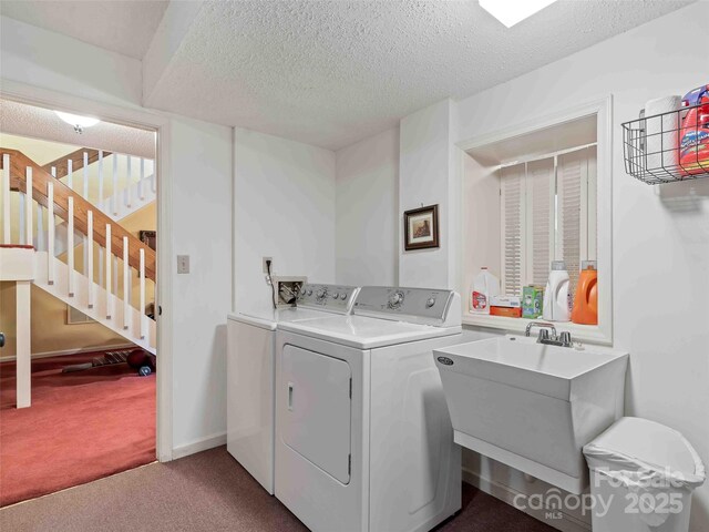 laundry room featuring washing machine and dryer, carpet, and a textured ceiling