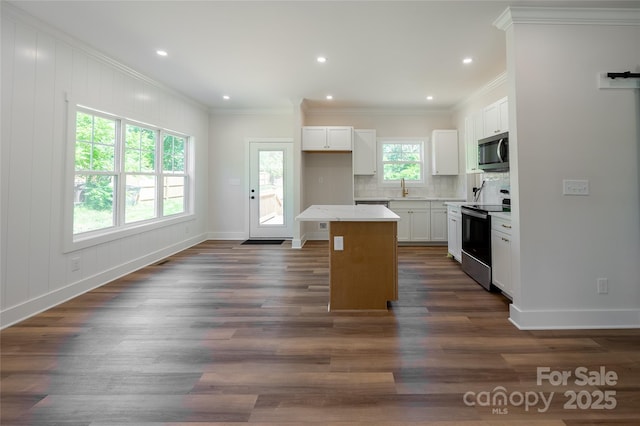 7426 Hambright Rd, Huntersville, NC 28078 - kitchen featuring range with electric stovetop, stainless steel microwave, tasteful backsplash, white cabinets, and crown molding