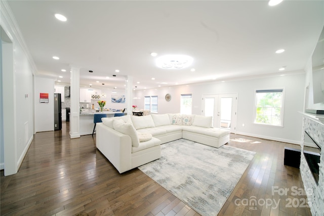 living area with a large fireplace, crown molding, baseboards, dark wood-style floors, and recessed lighting