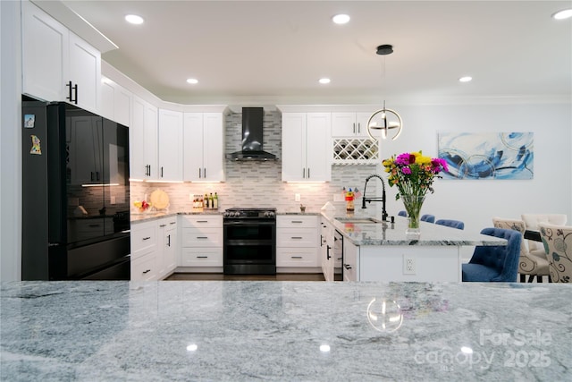 kitchen with black appliances, wall chimney exhaust hood, a sink, light stone counters, and white cabinetry