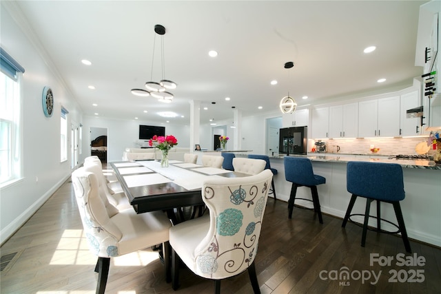 dining room featuring wood finished floors, crown molding, recessed lighting, and baseboards