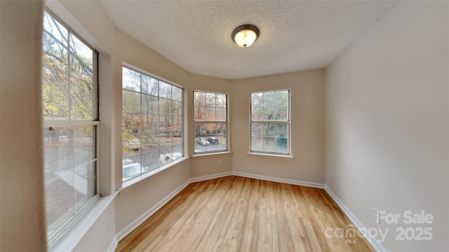 spare room featuring a textured ceiling, wood finished floors, and baseboards