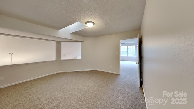 unfurnished room featuring a textured ceiling, carpet flooring, and baseboards