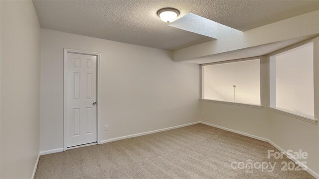 spare room featuring carpet floors, a textured ceiling, and baseboards
