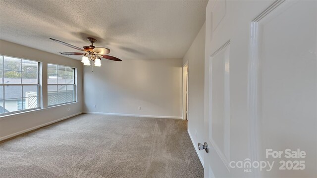 carpeted spare room with a ceiling fan, a textured ceiling, and baseboards