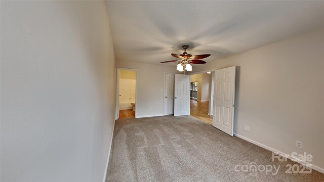 unfurnished bedroom with carpet flooring, baseboards, ensuite bathroom, and ceiling fan
