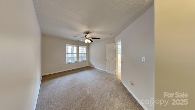 carpeted empty room featuring a textured ceiling, ceiling fan, and baseboards