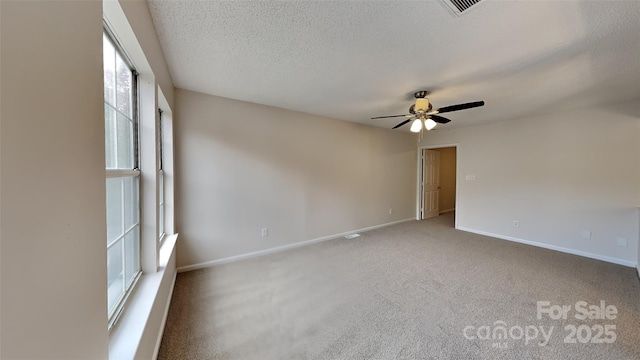 carpeted empty room with ceiling fan, baseboards, and a textured ceiling