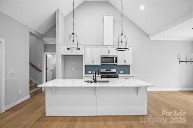 149 Beauchamp Oaks Ct, Advance, NC 27006 - kitchen featuring appliances with stainless steel finishes, a sink, high vaulted ceiling, white cabinets, and baseboards