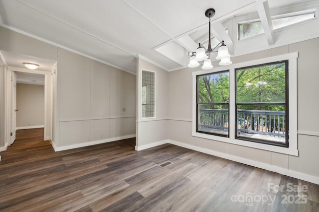 unfurnished dining area with a chandelier, wood finished floors, ornamental molding, baseboards, and beamed ceiling