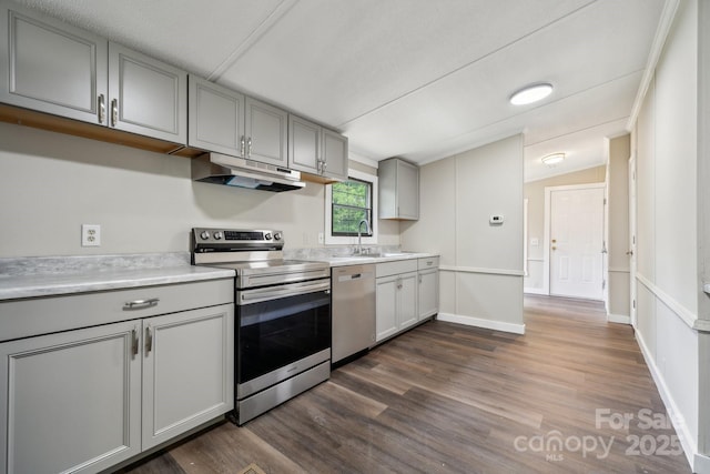 kitchen featuring appliances with stainless steel finishes, under cabinet range hood, gray cabinets, dark wood finished floors, and light countertops