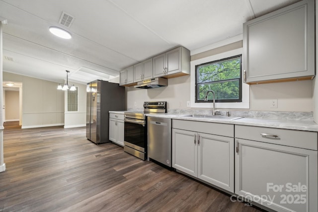kitchen with a sink, stainless steel appliances, gray cabinetry, light countertops, and dark wood-style floors