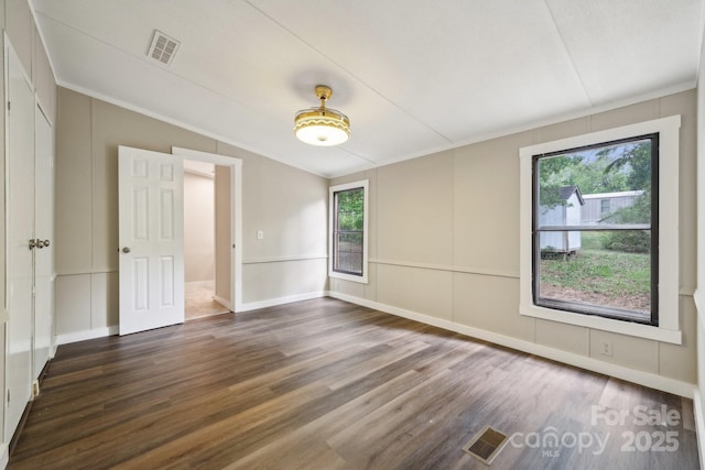empty room with lofted ceiling, wood finished floors, and crown molding