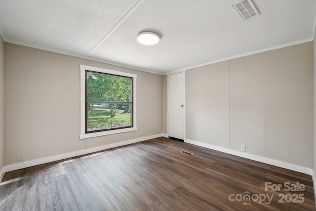spare room featuring dark wood-style flooring, baseboards, and a textured ceiling